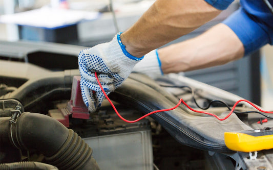 hands with gloves holding clips to car engine